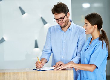 Male patient signing paperwork in dental office