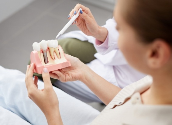 Dentist showing a patient a dental implant model