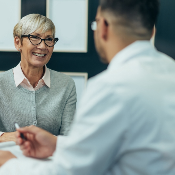 Smiling senior woman sitting across desk from dentist