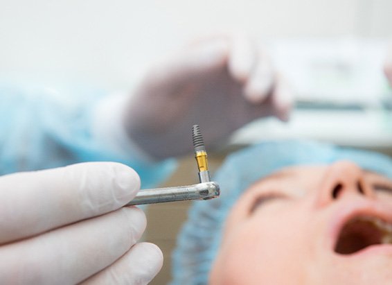 Oral surgeon about to place dental implant in patient’s jaw