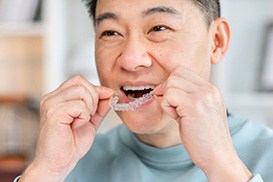 Person placing Invisalign tray onto upper teeth