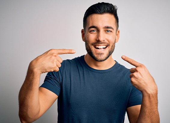 Smiling man pointing to his grin with both hands