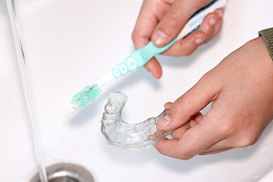 Invisalign trays being rinsed under running water
