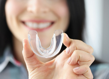 Dental implants patient in York holding mouthguard