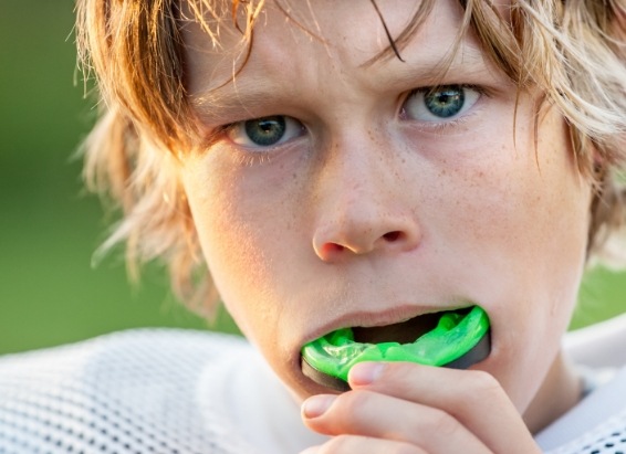 Young boy placing athletic mouthguard into his mouth