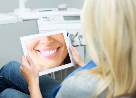 Dental patient looking at digital image of her smile on tablet
