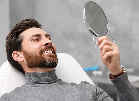 Man admiring smile after receiving dental crown