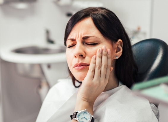 Woman holding her cheek in pain while visiting emergency dentist in York