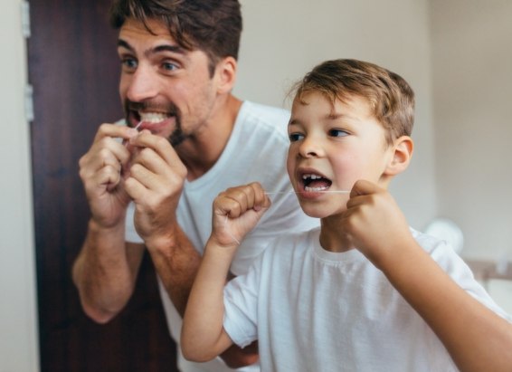 Father and young son flossing their teeth together