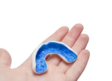 Patient holding blue and white mouthguard