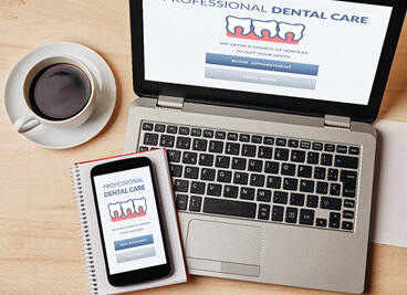 dental insurance forms on phone and laptop next to cup of coffe