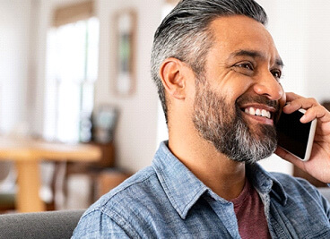 man smiling while talking on cellphone at home