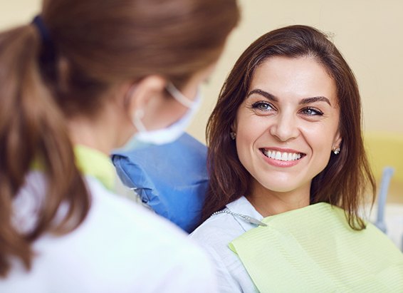a woman smiling and speaking with a dental hygienist