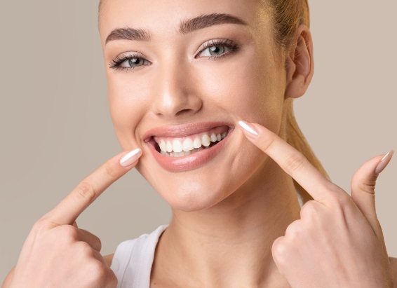 Woman pointing to her smile after gum disease treatment in York