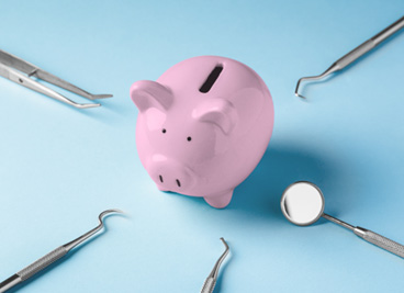 A piggy bank surrounded by dental tools on all sides