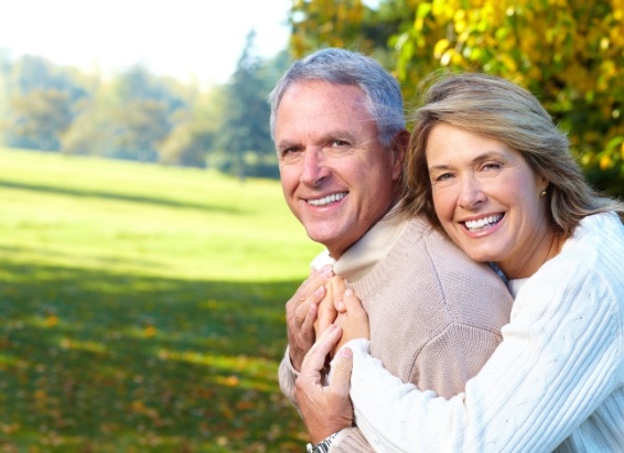Older man and woman hugging outdoors