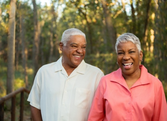 Older man and woman grinning in forest