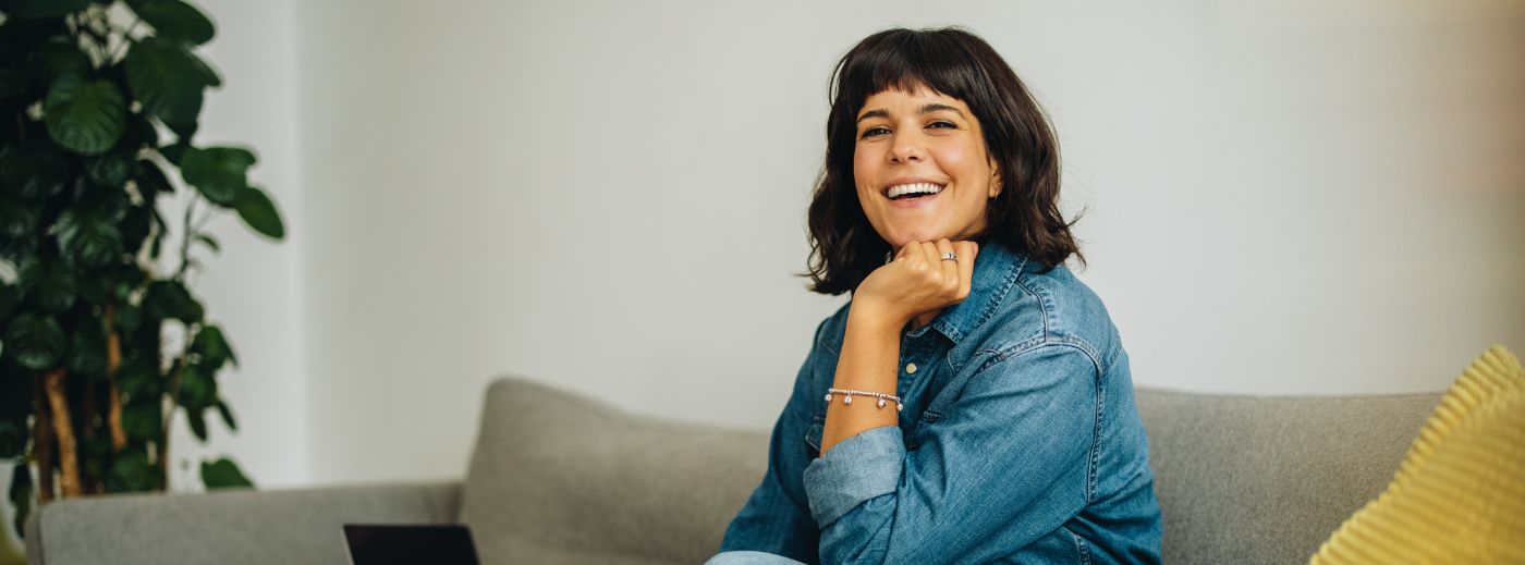 Smiling woman in denim shirt sitting on couch