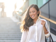 Smiling woman walking down outdoor staircase on sunny day