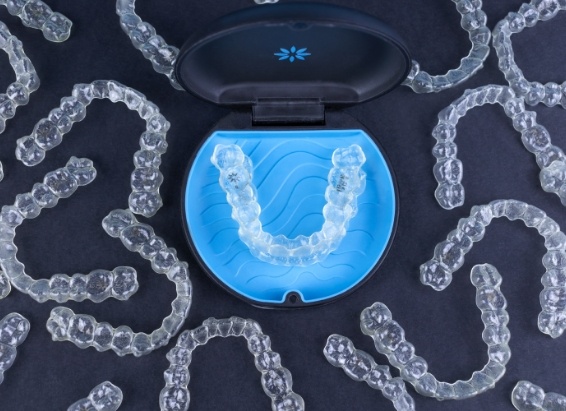 Invisalign clear aligner in carrying case surrounded by several other clear aligners
