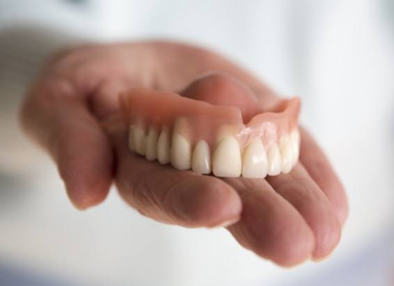 Hand holding a full denture