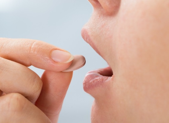 Close up of person placing a pill in their mouth