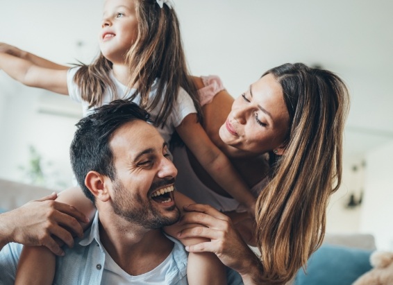 Family of three laughing on couch after dental services in York