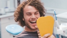 Young man looking at his smile in dental chair