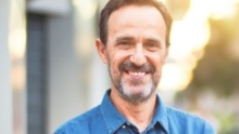 Man in denim shirt smiling outdoors