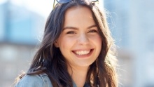 Woman with sunglasses grinning outdoors