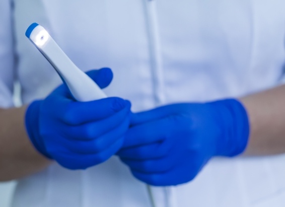 Two gloved hands holding an intraoral camera