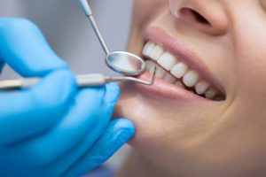 Close up of dental instruments next to woman’s teeth